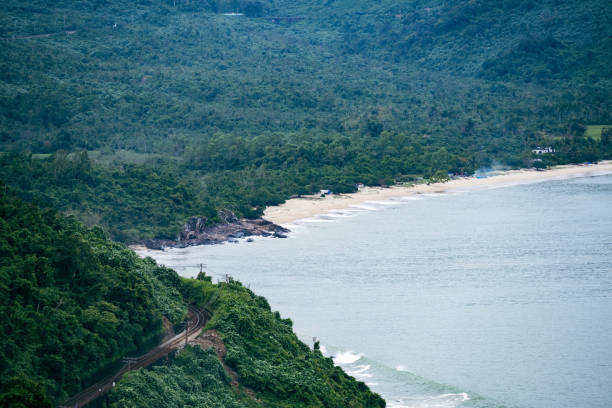 Discover the serene beach at Hai Van Pass in Da Nang, Vietnam, where people relax and enjoy the natural beauty on a cloudy day. This scenic spot offers a peaceful escape with stunning coastal views.