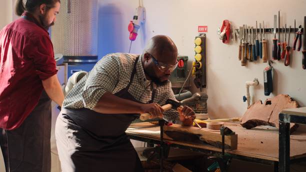 istock Artist making wood sculptures and coworker cleaning workbench 2158133528