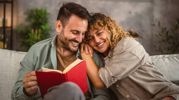 istock Boyfriend read a book while his girlfriend hug him at home 2158134416
