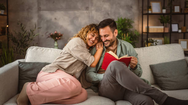 istock Boyfriend read a book while his girlfriend hug him at home 2158134798