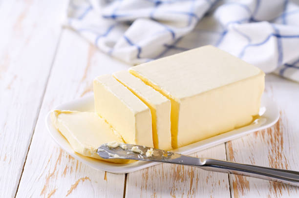istock piece of butter in a white ceramic butter dish on a light table. 2158134927