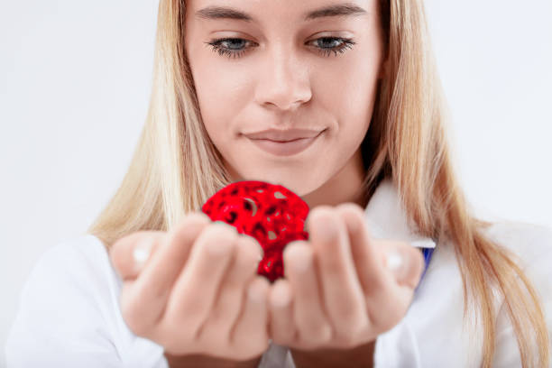 Scientist is carefully holding a red molecule model in her hands, her expression focused and intrigued by the scientific concept it represents