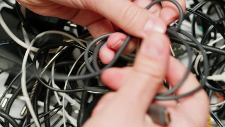 Young woman trying to untangle many various of wires close-up. Tangled wires and cables on table. Trying to untangle many messy and chaos cables