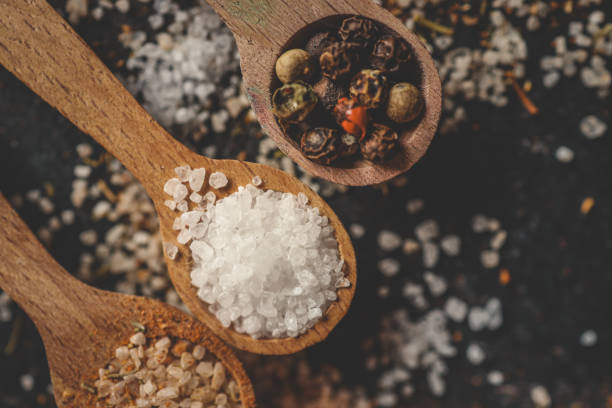 Wooden spoons with different spices on a black background, banner.