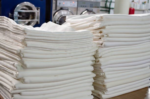 istock Closeup of folded white cloths in an industrial laundry. 2158143350