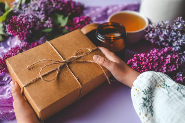 istock Gift box with a bow in hands in a homely atmosphere 2158144465