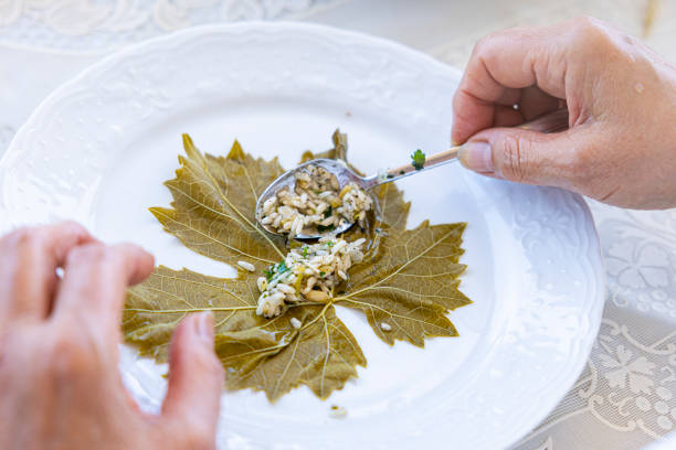 close up of making stuffed grape leaves with olive oil