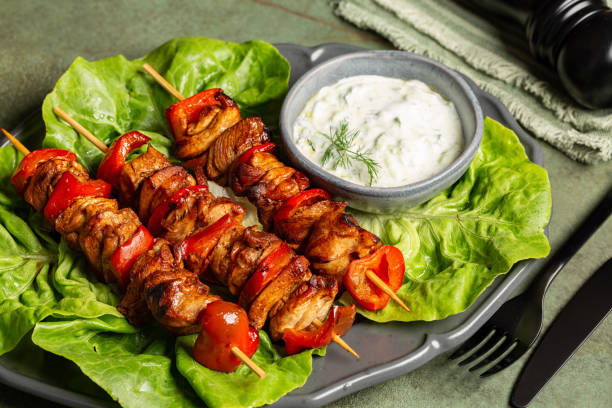 istock Mediterranean Grilled chicken kabobs or kebabs, made with marinated chicken and red bell peppers, threaded onto skewers. Green lattuga salad. Greek Tzatziki sauce made with yogurt, grated cucumber, lemon juice, olive oil. 2158146249