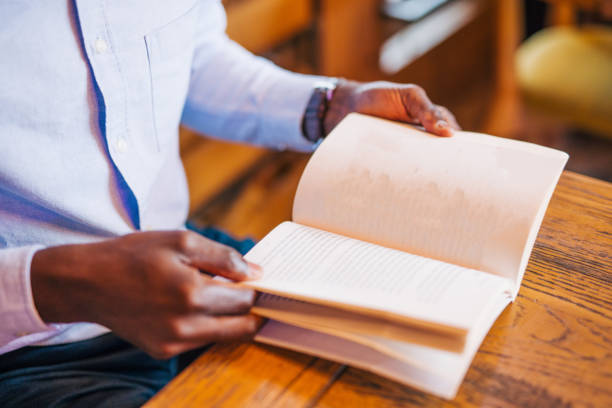 an adult handsome black male in cafe reading book.