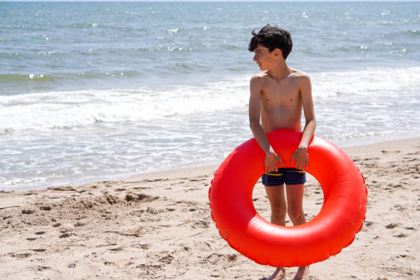 boy with red float looking towards the sea