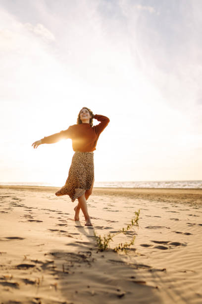 istock woman walking along a picturesque sandy beach 2158154265