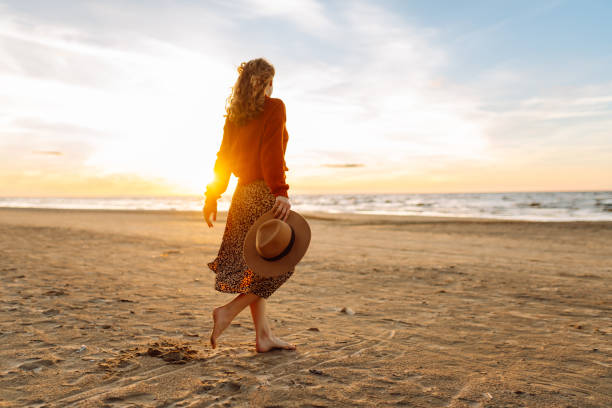 istock woman walking along a picturesque sandy beach 2158154316
