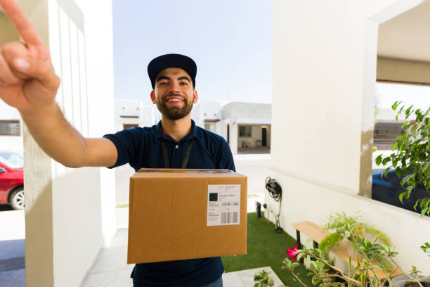 istock Courier in uniform rings a doorbell with a package, providing reliable delivery service and a smooth shopping experience 2158162000