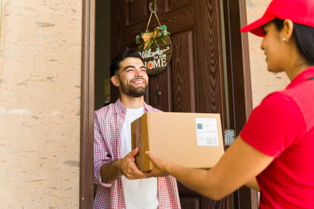 istock Customer joyfully accepting a delivery from a female courier at his doorstep 2158162622