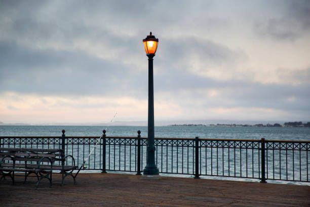 istock Street lamps illuminate pier at dusk 2158162662
