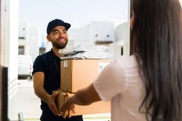 istock Joyful delivery man delivering cardboard boxes and package to a female customer at her front door 2158163661