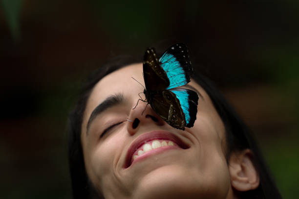 istock Morpho helenor achilles butterfly perched on smiling young woman's face in Mindo, Ecuador 2158164032