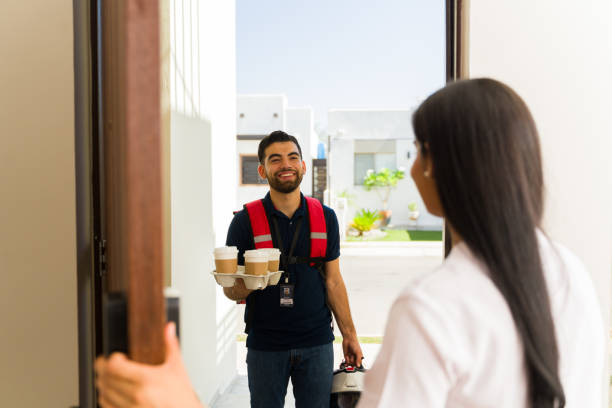istock Hispanic delivery man with a backpack and helmet delivering several drinks to a customer's home 2158164207