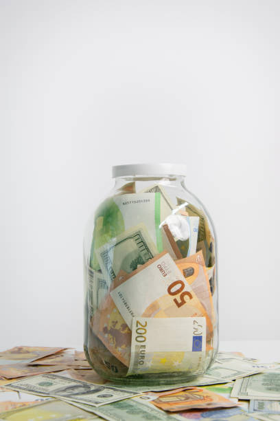 istock A glass jar filled with US dollars and euro bills sits on a table with scattered bills, ready to be saved or used 2158164600