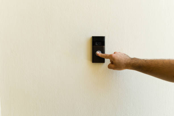 istock Hand of a man activating the smart doorbell on a pristine white wall, bringing a modern tech vibe to the home's entrance 2158166685