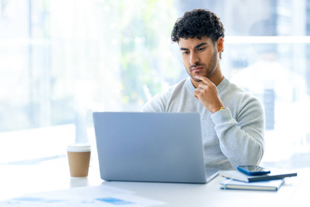 istock Serious Businessman working on a laptop computer in the office. He is looking contemplative and serious 2158171775