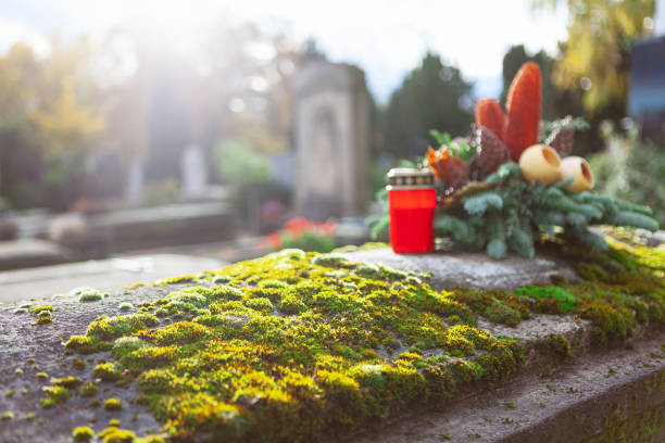 Candle and flowers on the headstone with moss