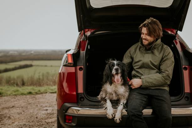 istock Man sitting in car trunk with dog 2158176242