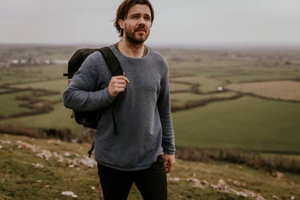 istock Man wearing long sleeve shirt, walking on hill 2158176431