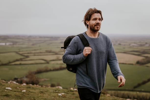 istock Man wearing long sleeve shirt, walking on hill 2158176442