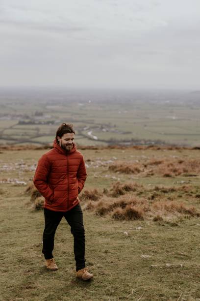 istock Man wearing orange puffer jacket, walking on hill 2158176652