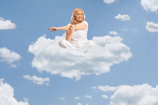 Woman in white clothes practicing yoga and stretching arm up in the sky