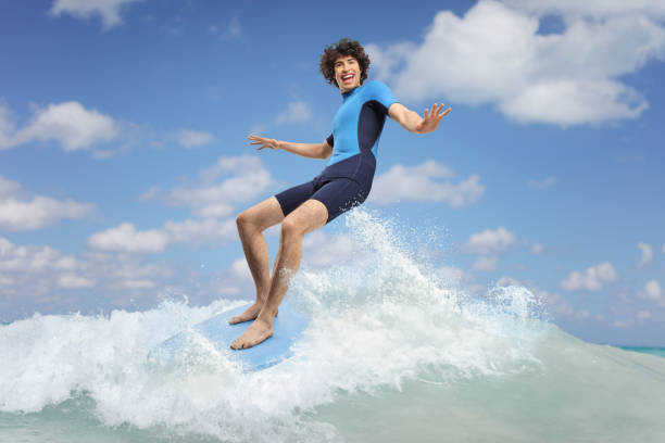 istock Young man in a wetsuit riding a surfboard on a wave 2158182184