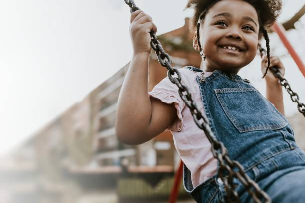 istock Happy African girl on playground swing 2158183555