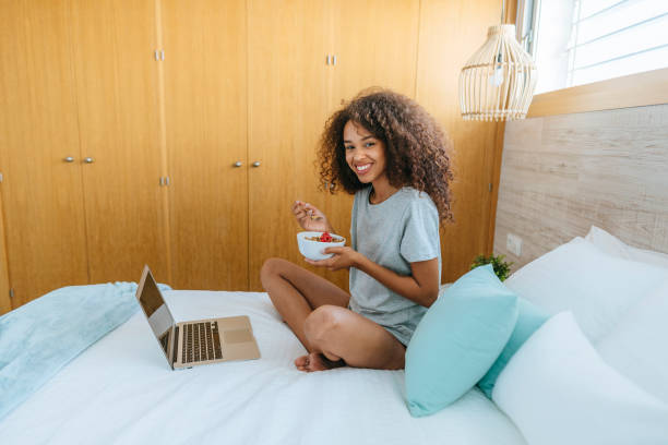 istock Woman eating cereal in bed next to laptop 2158185914