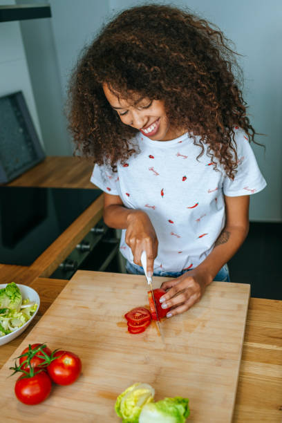 istock Woman in the kitchen cutting tomato on cutting board 2158187574