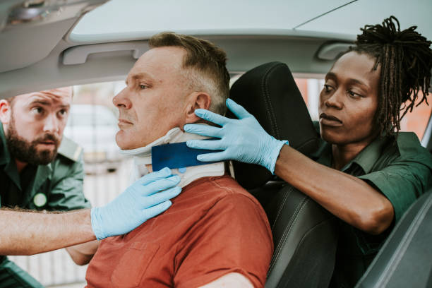 paramedic placing a cervical collar to an injured man from car accident - fiziksel yaralanma stok fotoğraflar ve resimler