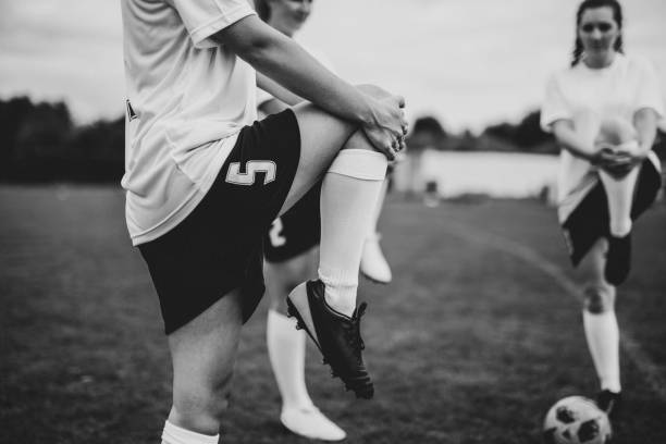 Soccer players kick the ball in competition. Football adult game. Players in two teams compete for the ball. Footballers running on the grass pitch