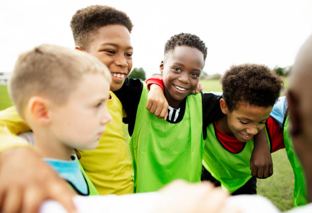 istock Junior football team huddling together 2158192526