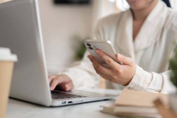 istock A businesswoman working remotely from a cafe, working on her laptop while using her smartphone. 2158194265
