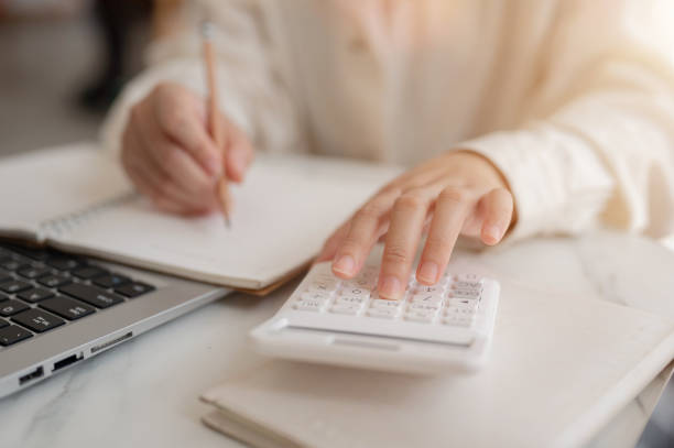 istock A close-up image of a woman using a calculator, examining her expenses, planning her savings 2158194280