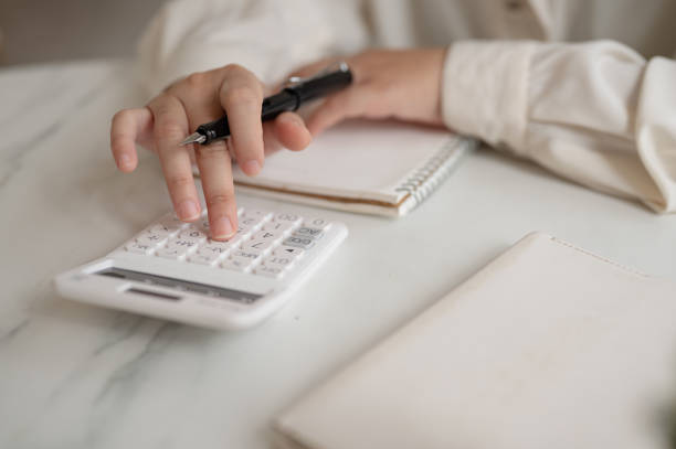 istock A close-up image of a woman using a calculator at a table, checking and calculating her budget. 2158194292