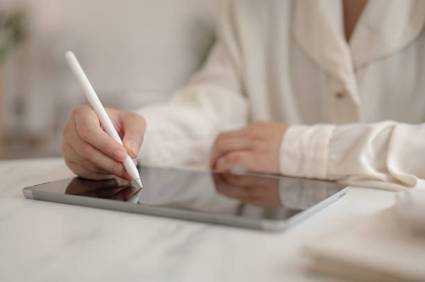 istock A woman working remotely from a cafe, holding a stylus pen and working on her digital tablet. 2158194319