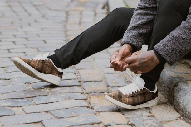 istock Man tying shoelaces on cobblestone street 2158194800
