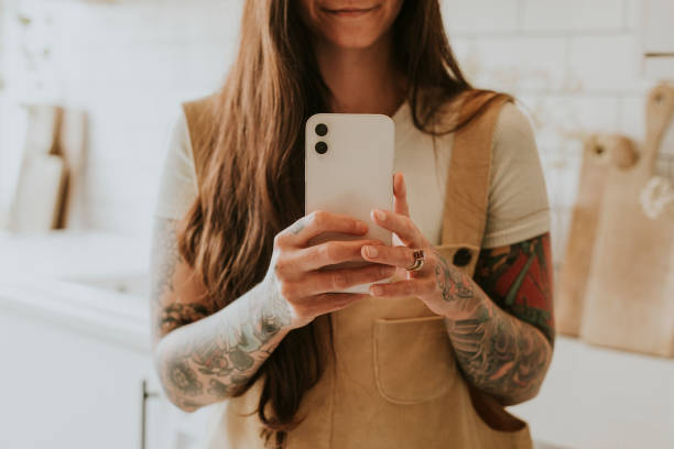 istock Tattooed woman smartphone in a bright kitchen 2158197830