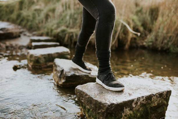 Woman enjoying outdoors adventure crossing the stream