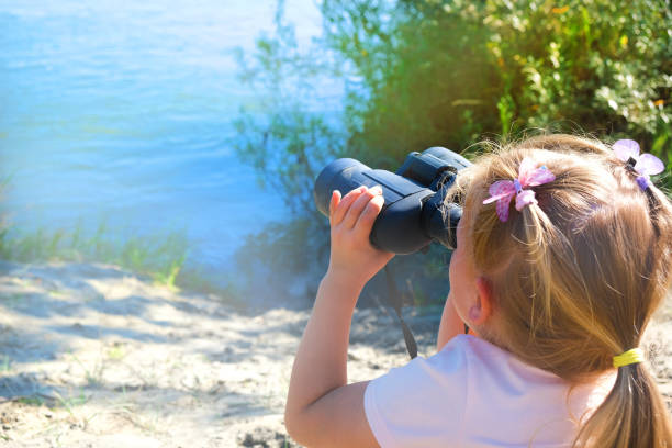 Cute little hiker girl looking with binoculars at sunset.Image is intentionally with grain and toned.