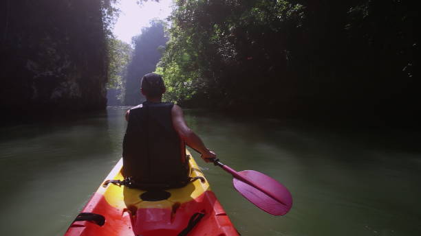 istock Man smoothly navigates kayak savoring views of jungle 2158199815