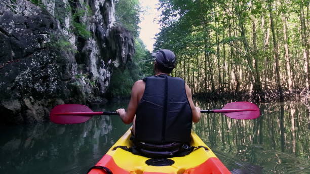 istock Tourist in kayak holds paddle pointing with hand at cliff 2158200539