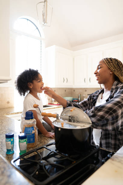 istock Young mother feeding young child in the kitchen 2158201055