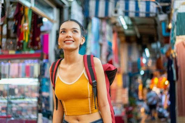 istock Happy Female Tourist Exploring Vibrant Weekend Market with Backpack 2158201110